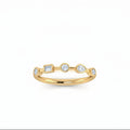 A delicate yellow gold ring featuring five small multi shaped-cut lab grown diamondsin spaced out setting, diamonds 1/2 in a row, photographed on a clean white background.
