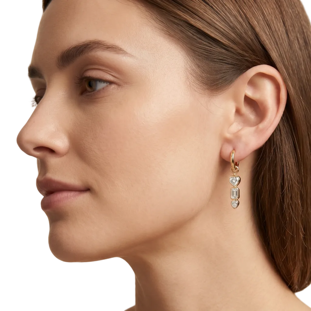 Yellow Gold bezel set drop earrings with heart and baguette cut and pear diamonds on a white background on a model.