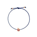 A navy blue cord bracelet with a small rose gold apple charm set with purple gemstones, shown on a plain white background.