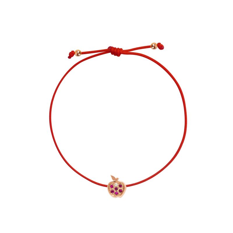 A red adjustable cord bracelet featuring a small rose gold apple charm embellished with purple gemstones, set against a plain white background.
