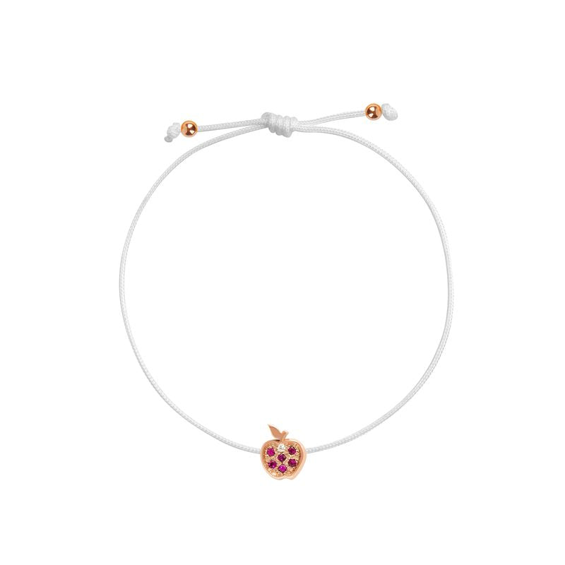 A delicate white cord bracelet featuring a small rose gold apple charm set with pink gemstones, shown on a plain white background.