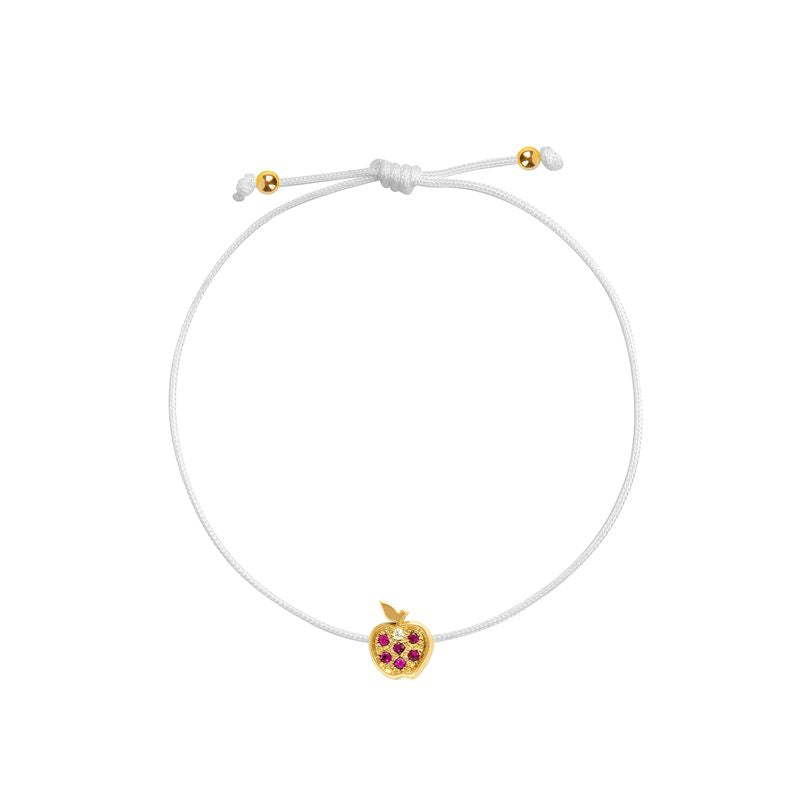 A delicate white cord bracelet featuring a small gold apple charm embellished with red gemstones, displayed on a clean white background.