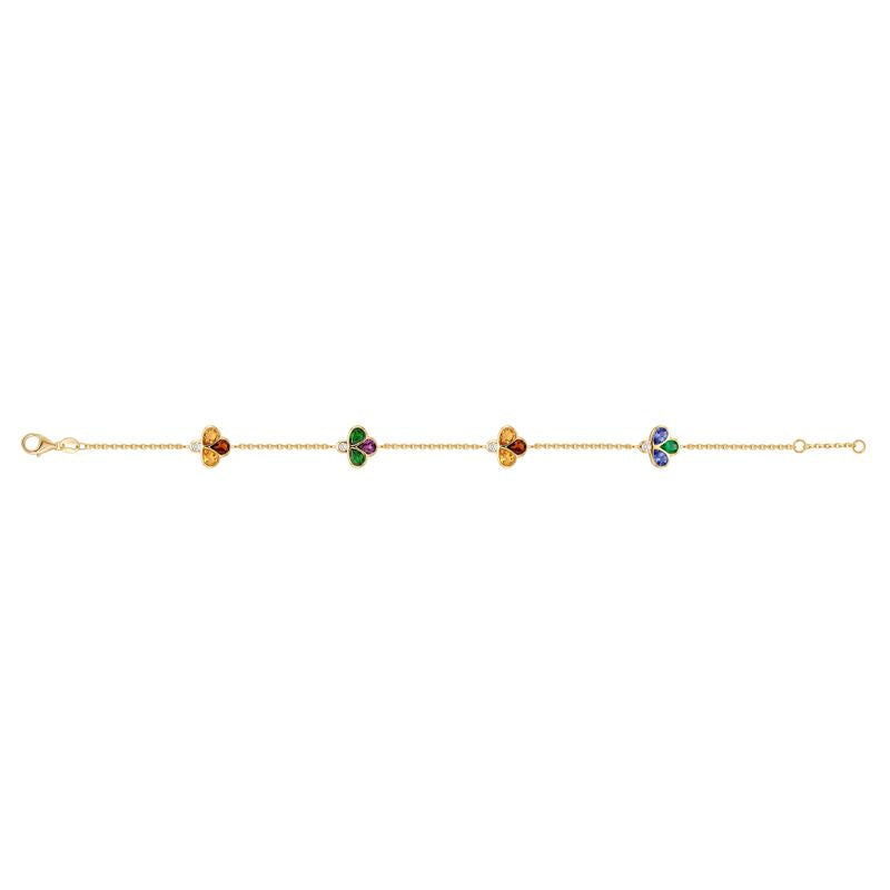 A delicate gold chain bracelet featuring four small clover motifs in different colors (orange, green, yellow, purple) spaced evenly along the chain, set against a plain white background.