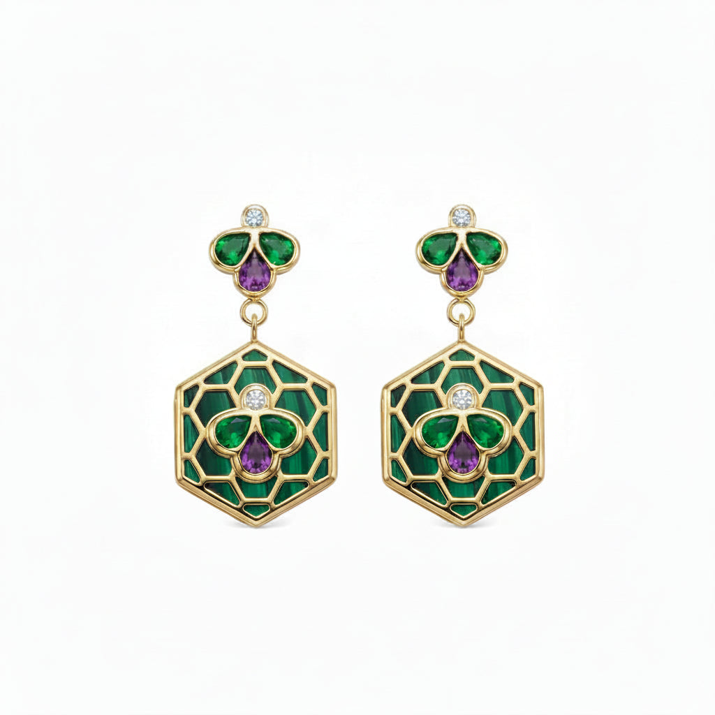 A pair of gold drop earrings featuring green and purple enamel floral motifs, with small round diamonds, set against a plain white background.