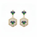 A pair of gold drop earrings featuring a hexagonal openwork design with white inlay, accented by blue and green enamel-like sections and a small round diamond at the top.
