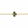A gold chain bracelet featuring a central clover charm with green and purple stones, set against a plain white background.