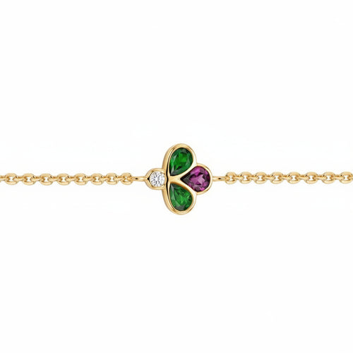 A gold chain bracelet featuring a central clover charm with green and purple stones, set against a plain white background.