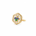 A gold hexagonal ring featuring an openwork honeycomb pattern with white enamel inlay and a central clover motif made of blue and green stones, accented by a small clear gemstone.