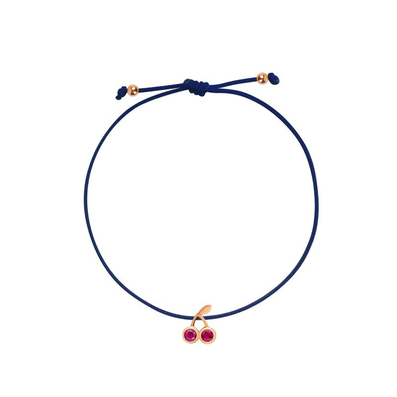 A navy blue cord bracelet with a gold-tone cherry charm featuring two small red gemstones, shown on a plain white background.