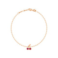 A delicate rose gold chain bracelet with a cherry charm featuring two red gemstones and a small clear accent stone, displayed on a clean white background.