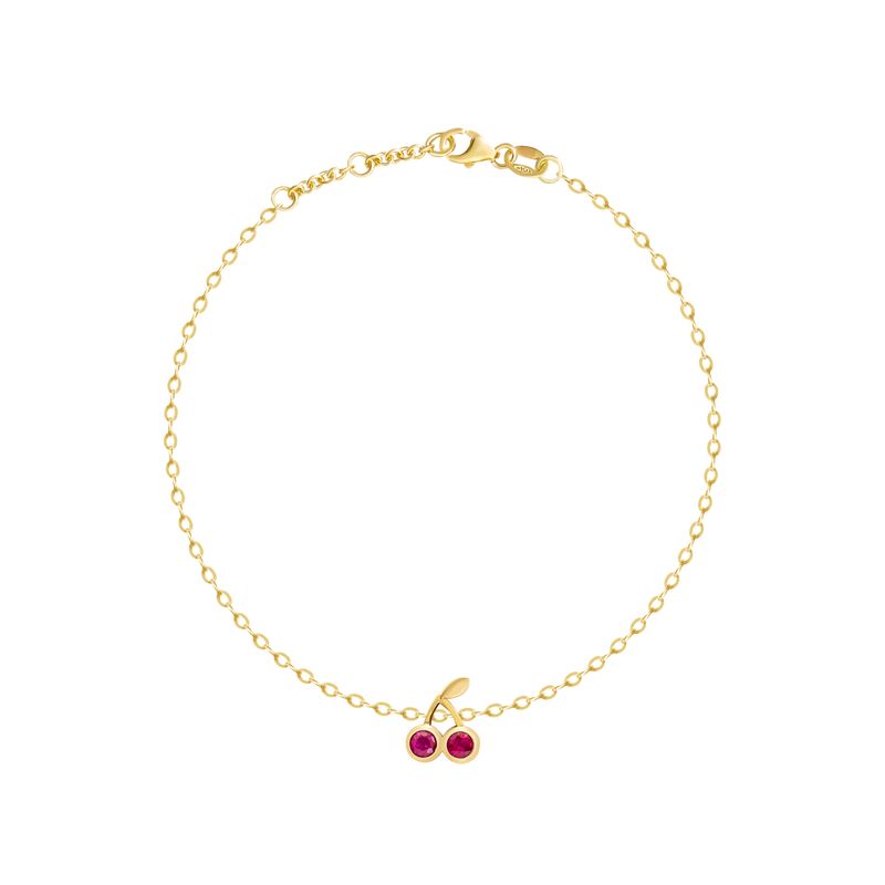 A delicate yellow gold chain bracelet with a small cherry charm featuring two red gemstones, displayed on a clean white background.