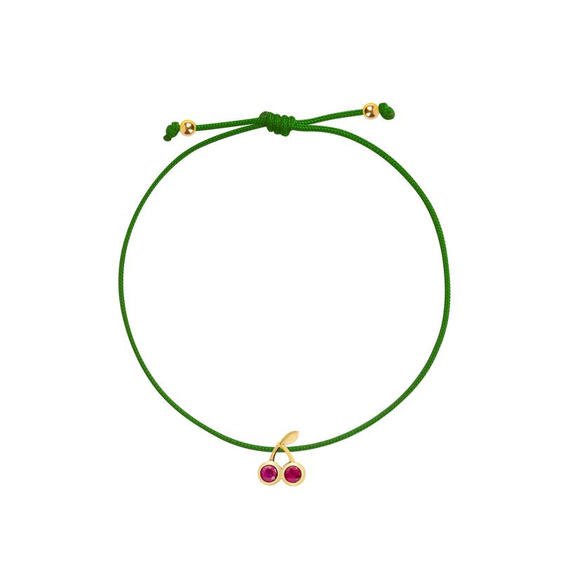 A green adjustable cord bracelet featuring a small gold-tone cherry charm with two pinkish-red gemstone centers, displayed on a clean white background.