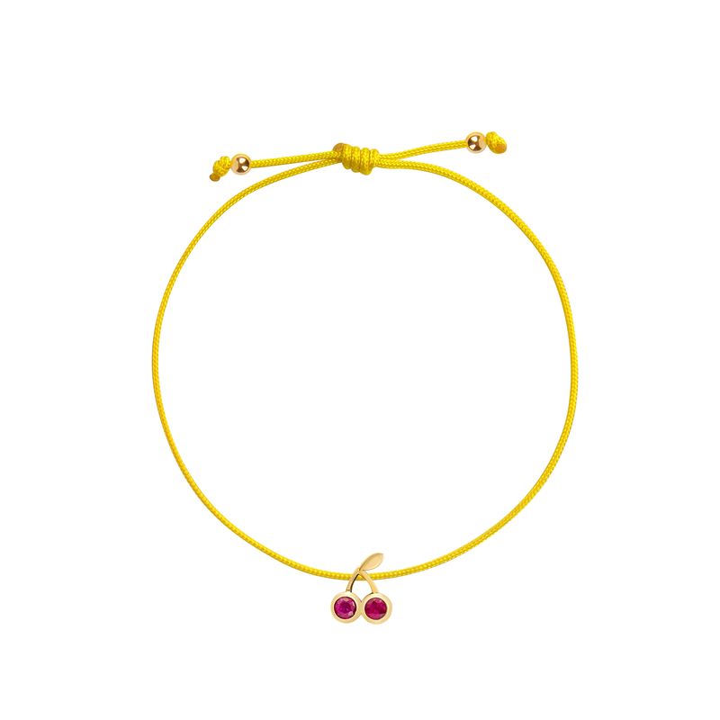 A delicate yellow cord bracelet featuring a small gold cherry charm with two red gemstone accents, displayed on a clean white background.
