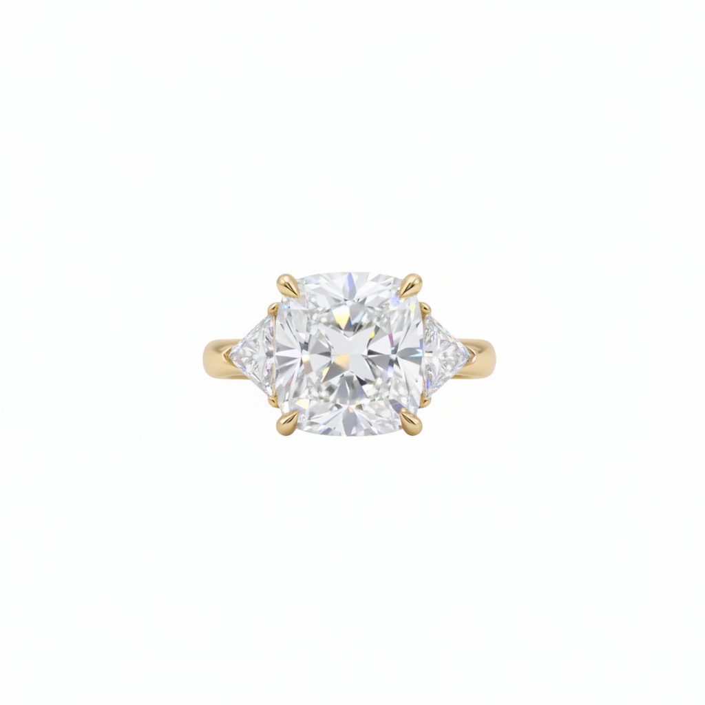 A yellow gold three-stone ring featuring a large cushion brilliant-cut center lab grown diamond flanked by two smaller trillion lab grown diamonds, set against a plain white background.

