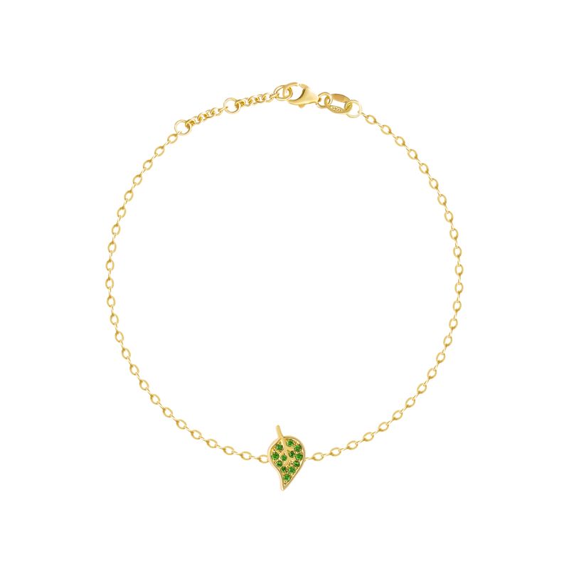 A delicate yellow gold chain bracelet with a small leaf-shaped charm paved with green stones, displayed on a clean white background.
