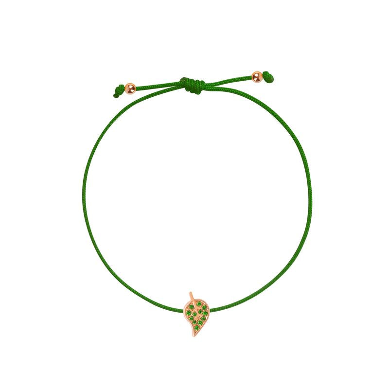 A delicate green cord bracelet featuring a small leaf- shaped charm with green stones and a rose gold border, displayed on a clean white background.