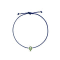A navy blue cord bracelet featuring a small white gold leaf charm embellished with green stones, displayed on a clean white background.