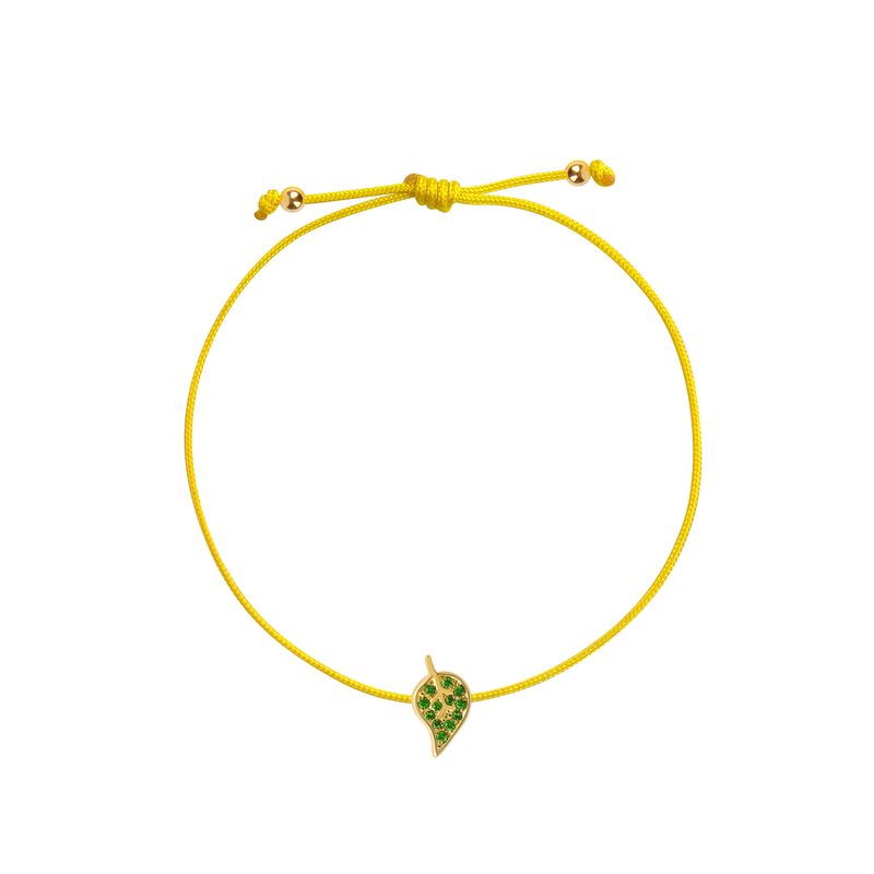 An yellow cord bracelet featuring a small yellow gold leaf charm embellished with green stones, displayed on a clean white background.