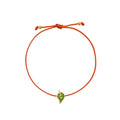 An orange cord bracelet featuring a small yellow gold leaf charm embellished with green stones, displayed on a clean white background.
