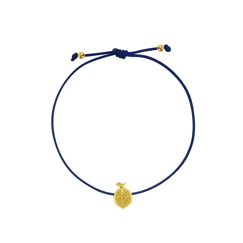 A delicate navy cord bracelet featuring a small textured yellow gold lemon charm and adjustable sliding knot with gold accent beads, shown on a plain white background.