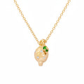 A gold pendant necklace featuring a stylized, textured lemon pendant with small white diamonds and a green emerald color accent gemstones, shown on a white background.