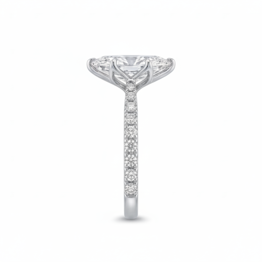 A platinum solitaire engagement ring featuring a marquise brilliant-cut center stone and pavé-set accent stones along the shank, shown against a plain white background from the side standing view.