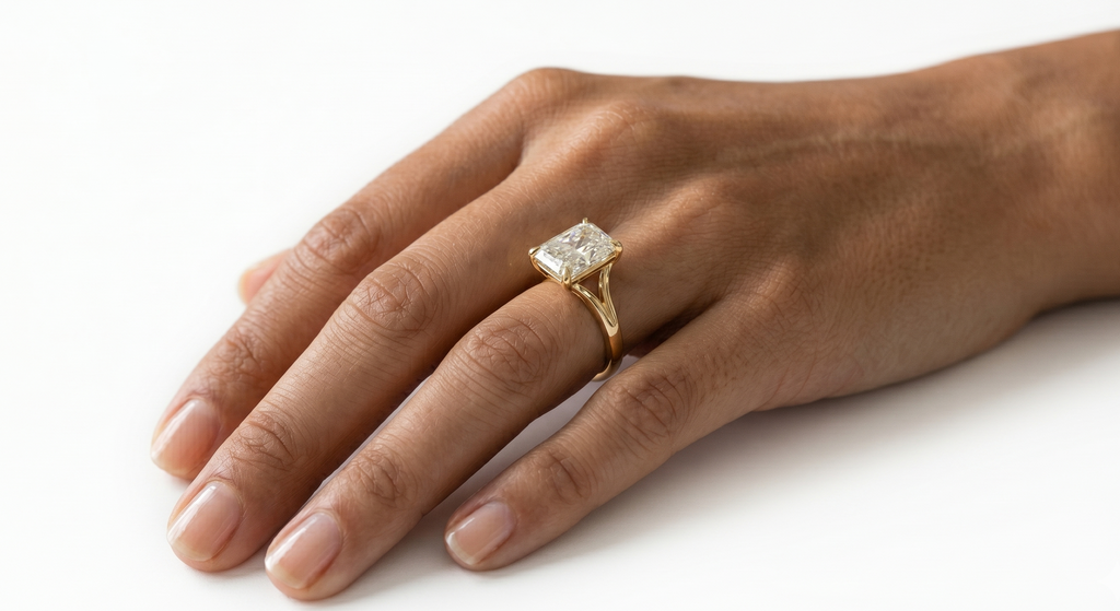 Yellow Gold Solitaire Ring with Radiant center lab grown diamond on models hand in a white background.