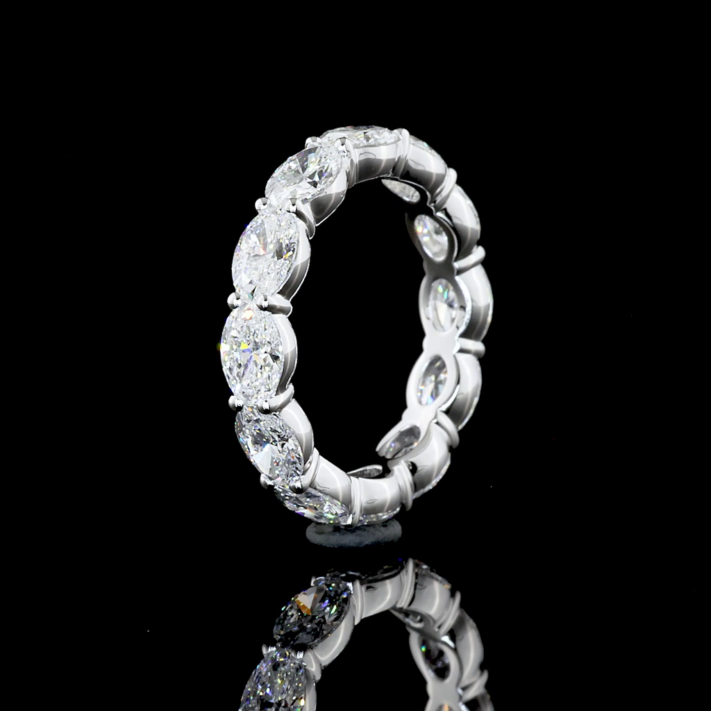 A white gold eternity ring featuring a continuous row of oval-cut lab grown diamonds, photographed on a seamless black background.