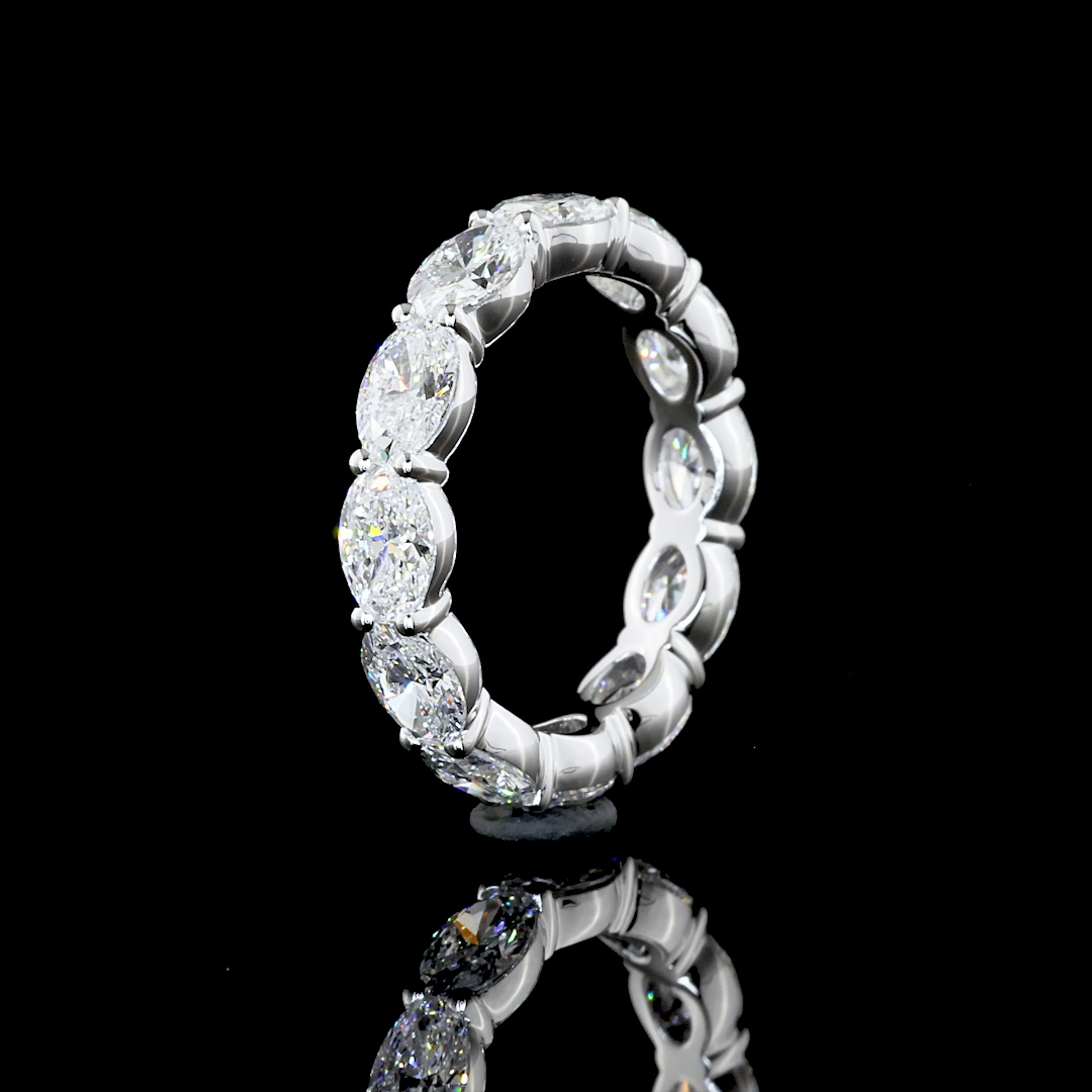 A white gold eternity ring featuring a continuous row of oval-cut lab grown diamonds, photographed on a seamless black background.
