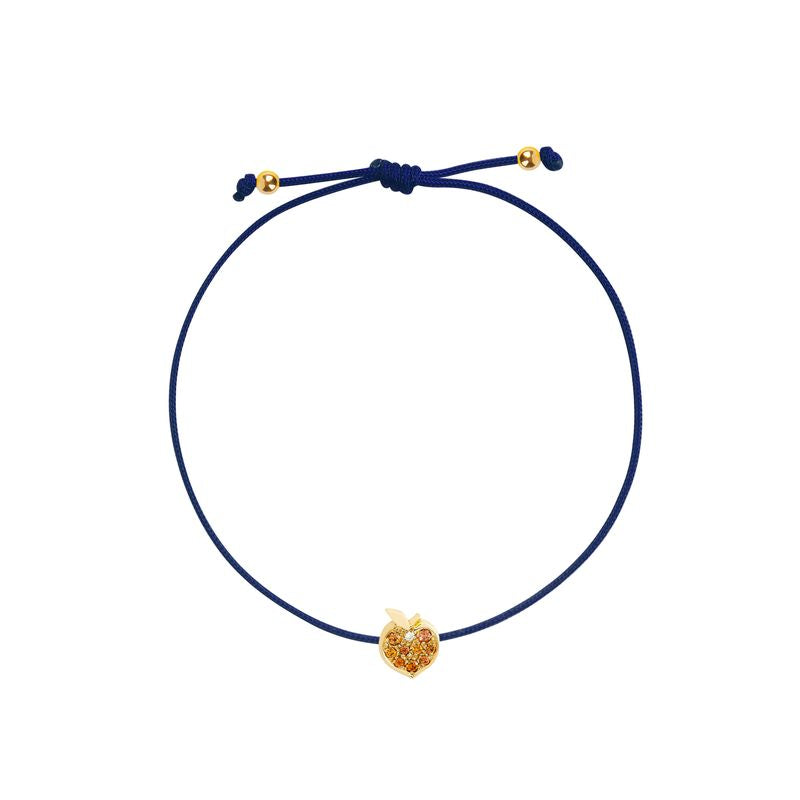 A navy blue cord bracelet featuring a small gold peach-shaped charm adorned with tiny orange stones, presented on a solid white background.