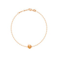 A delicate rose gold chain bracelet featuring a small, textured apple-shaped charm in the center, displayed on a clean white background.