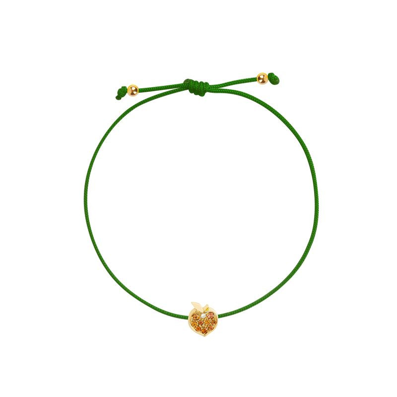 A green cord bracelet featuring a small gold peach-shaped charm adorned with tiny orange stones, presented on a solid white background.