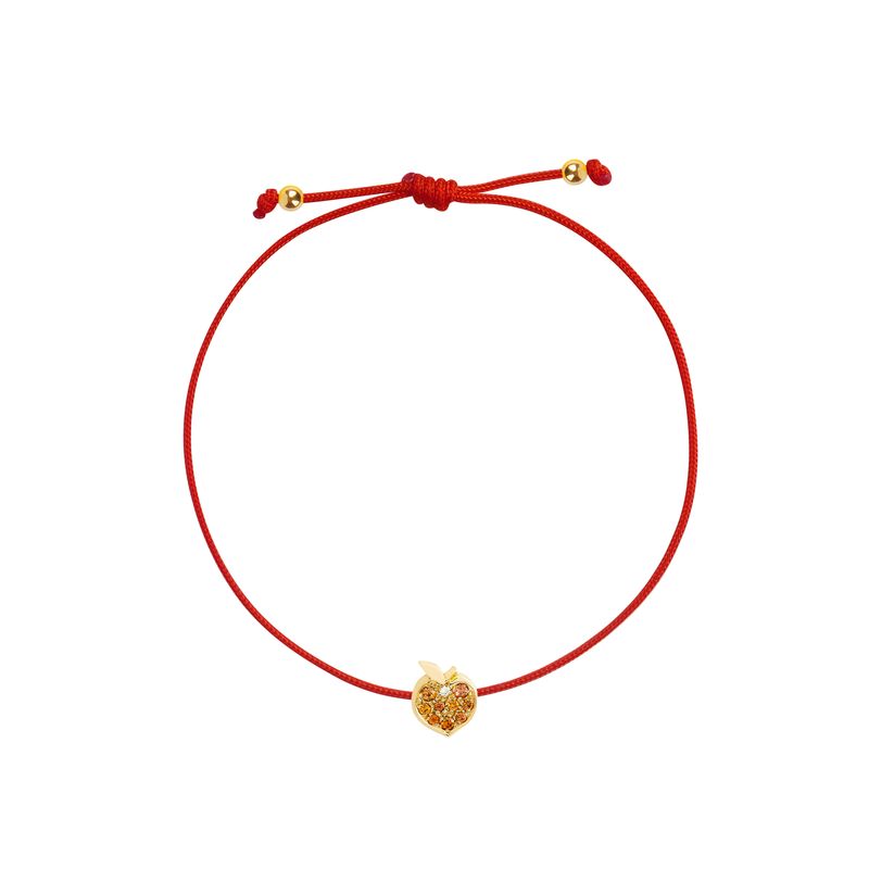A red cord bracelet featuring a small gold peach-shaped charm adorned with tiny orange stones, presented on a solid white background.