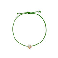 A green adjustable cord bracelet featuring a small apple-shaped charm with white gold and orange details, displayed on a clean white background.