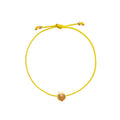 A yellow cord bracelet featuring a small gold peach-shaped charm adorned with tiny orange stones, presented on a solid white background.