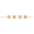A gold chain bracelet featuring four ornate circular filigree medallions, each set with a light blue or yellow stone and a central gold bead, displayed on a clean white background.
