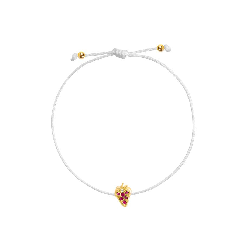 A delicate white cord bracelet featuring a small yellow gold strawberry charm adorned with red gemstones, shown on a plain white background.