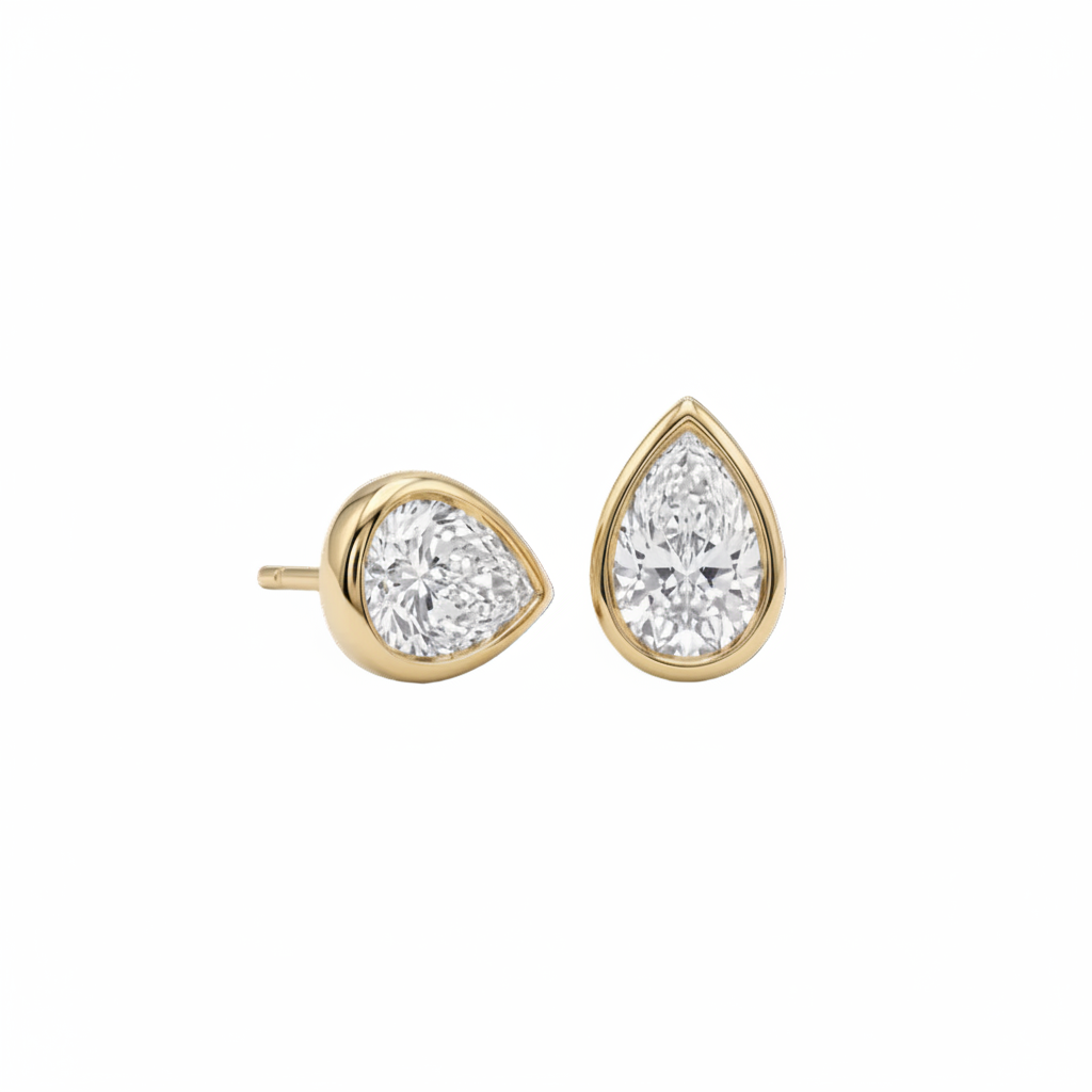 A pair of pear-shaped diamond bezel set stud earrings in yellow gold, shown against a plain white background.