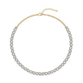 A gold chain necklace with a double row of sparkling clear pavé-set round diamonds in oval shaped design, displayed on a clean white background.