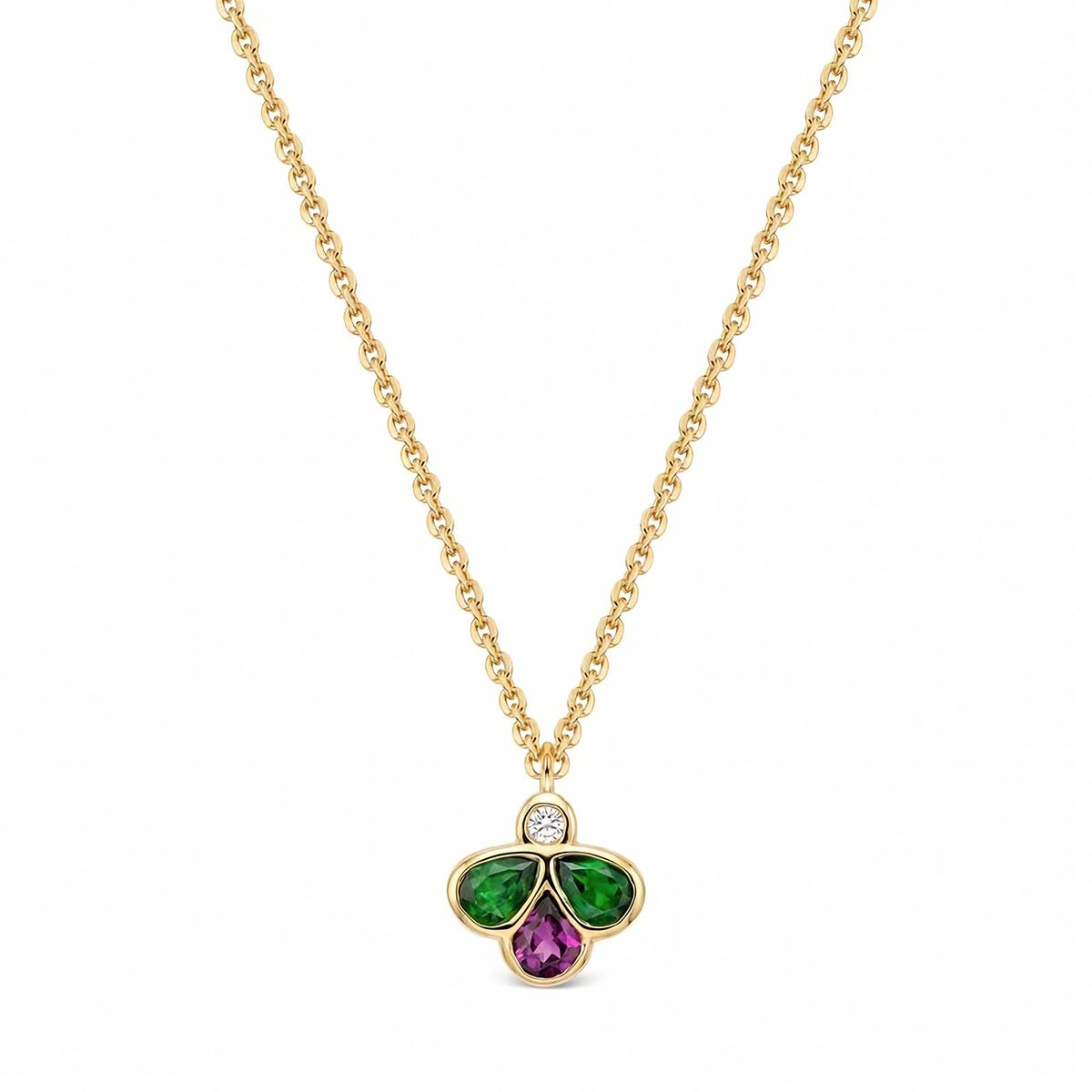 A gold chain necklace with a clover-shaped pendant featuring a small round diamond at the top, a green teardrop-shaped stones on the left and right, and a purple teardrop-shaped stone in the middle, set against a plain white background.