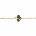 A gold chain bracelet featuring a central clover charm with green and purple stones, set against a plain white background.