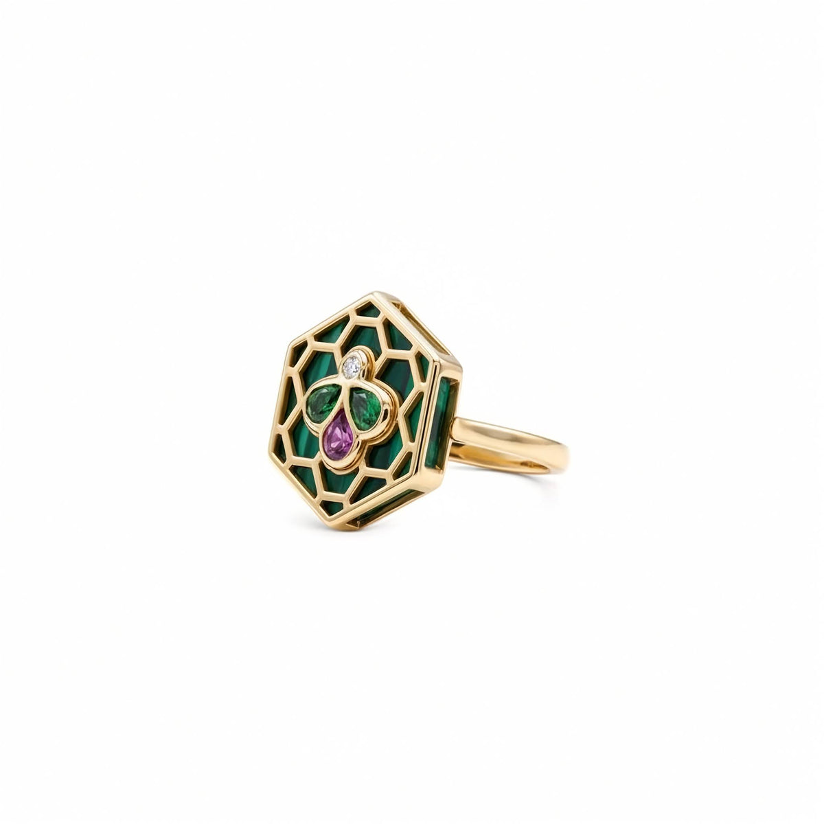 A gold hexagonal ring featuring green enamel inlay, a central green and purple clover motif, and a small clear gemstone, shown on a plain white background.