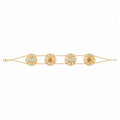 A gold chain bracelet featuring four ornate circular filigree medallions, each set with a light blue or yellow stone and a central gold bead, displayed on a clean white background.