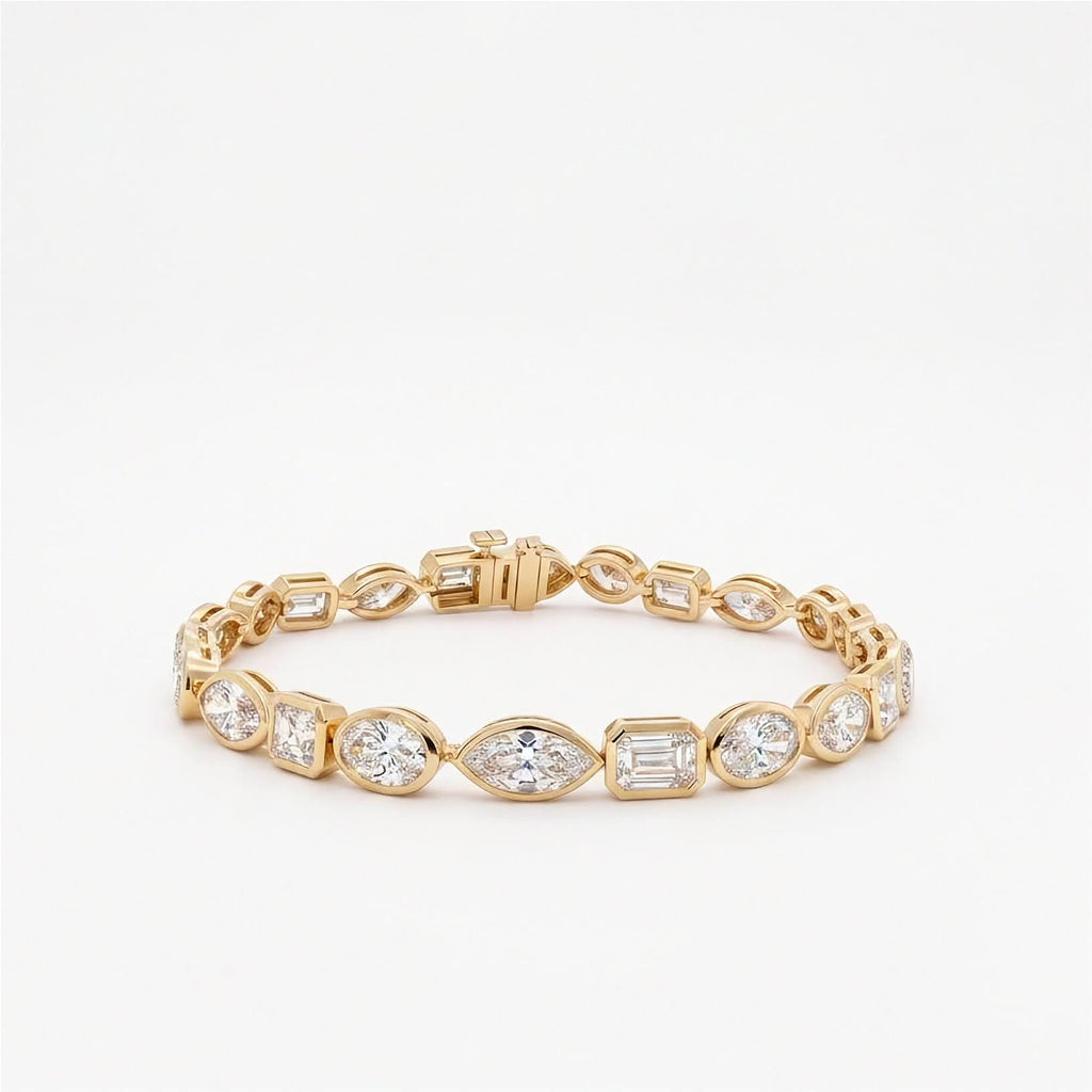 10.25 ctw mixed shape bezel set lab diamond tennis bracelet in 14k yellow gold with oval, marquise, and emerald cut diamonds on light gray background. 