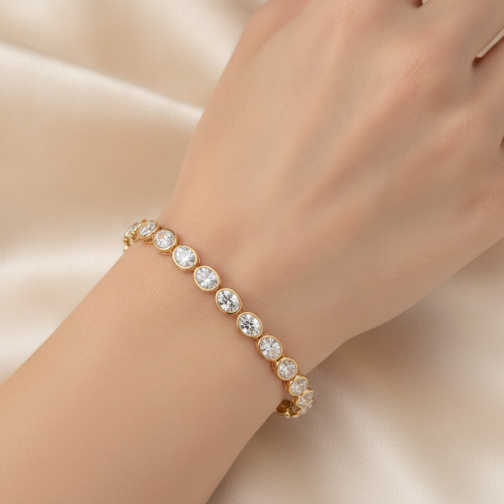 14K yellow gold bezel set oval lab grown diamond tennis bracelet 10.70 ctw Inga Fine Jewelry shown on models hand on silk beige background.