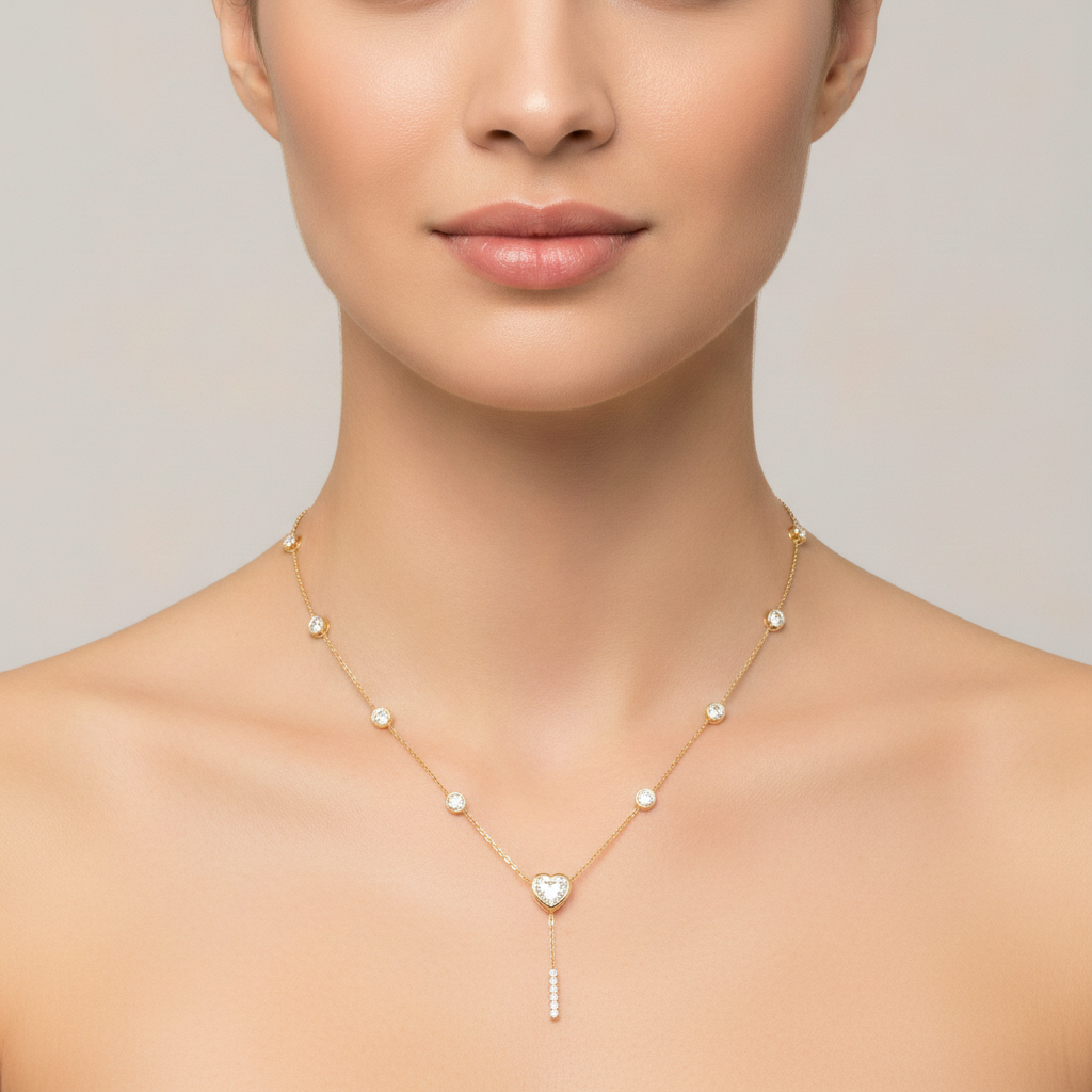 14K yellow gold heart diamond lariat necklace with bezel set station diamonds and pave drop bar on a model and light gray background