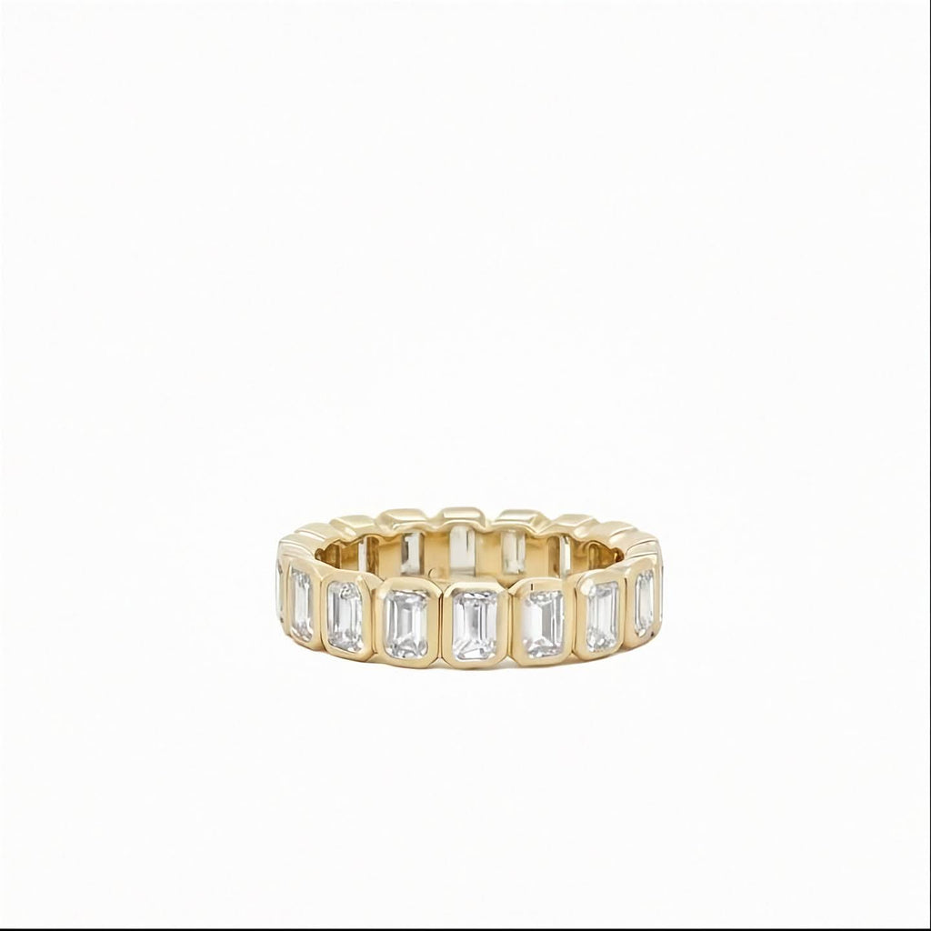 14K yellow gold bezel set emerald cut lab grown diamond eternity band ring 2.67 ctw Inga Fine Jewelry on white background.