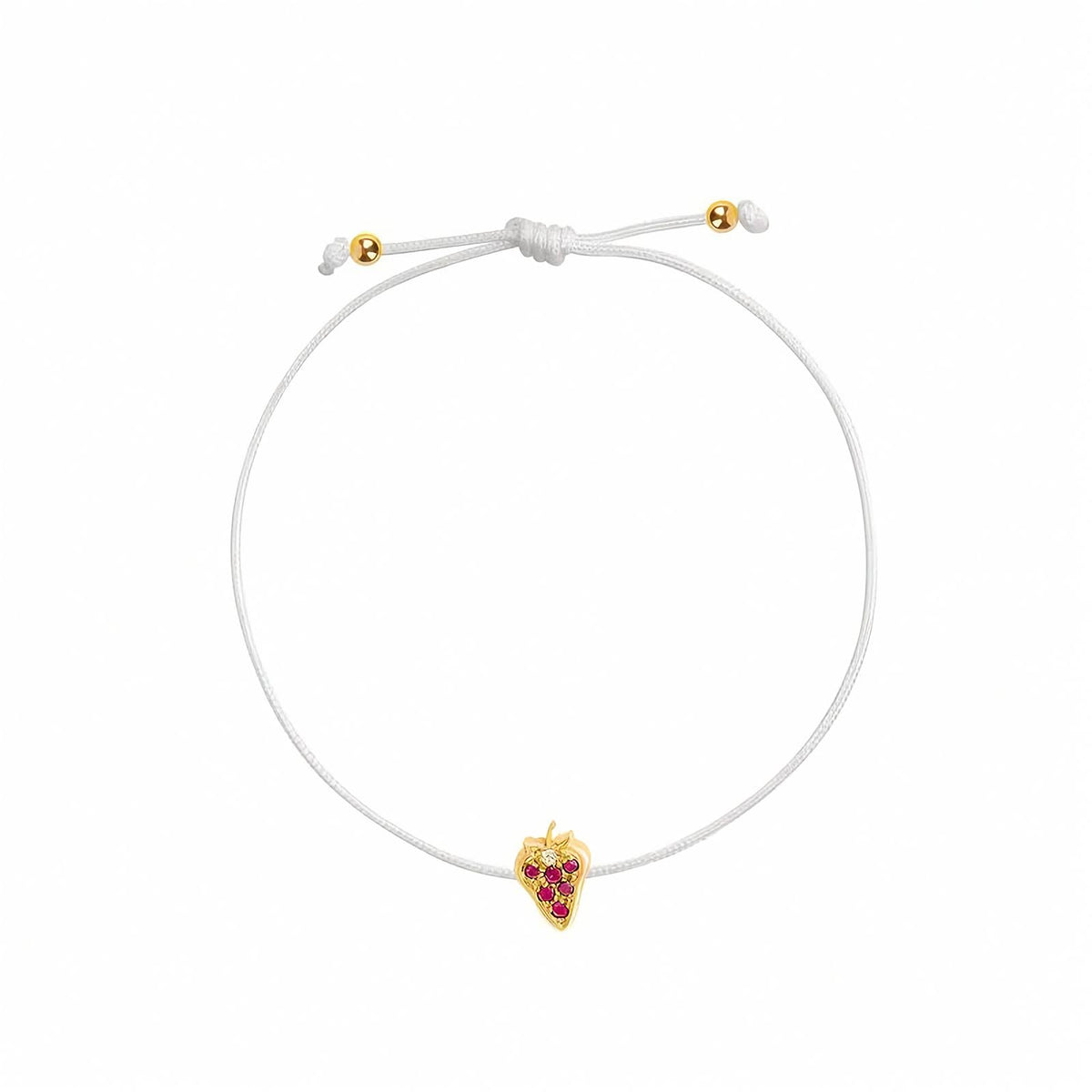 A delicate white cord bracelet featuring a small yellow gold strawberry charm adorned with red gemstones, shown on a plain white background.