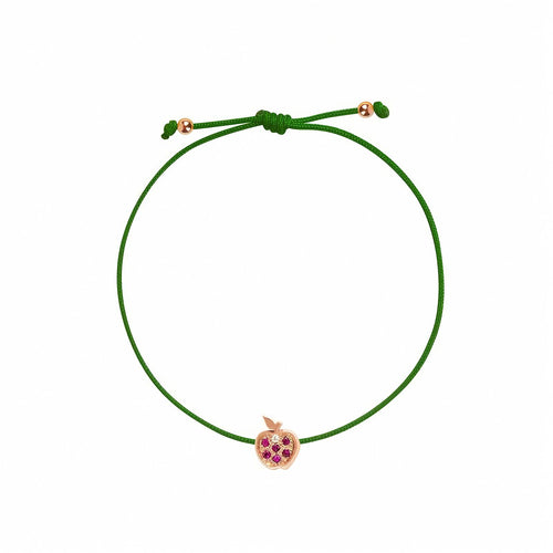 Rosmundo collaboration 18k rose gold apple string bracelet with natural rubies and diamond on adjustable macrame cord. A green cord bracelet with a small rose gold apple charm set with purple gemstones, shown on a plain white background.