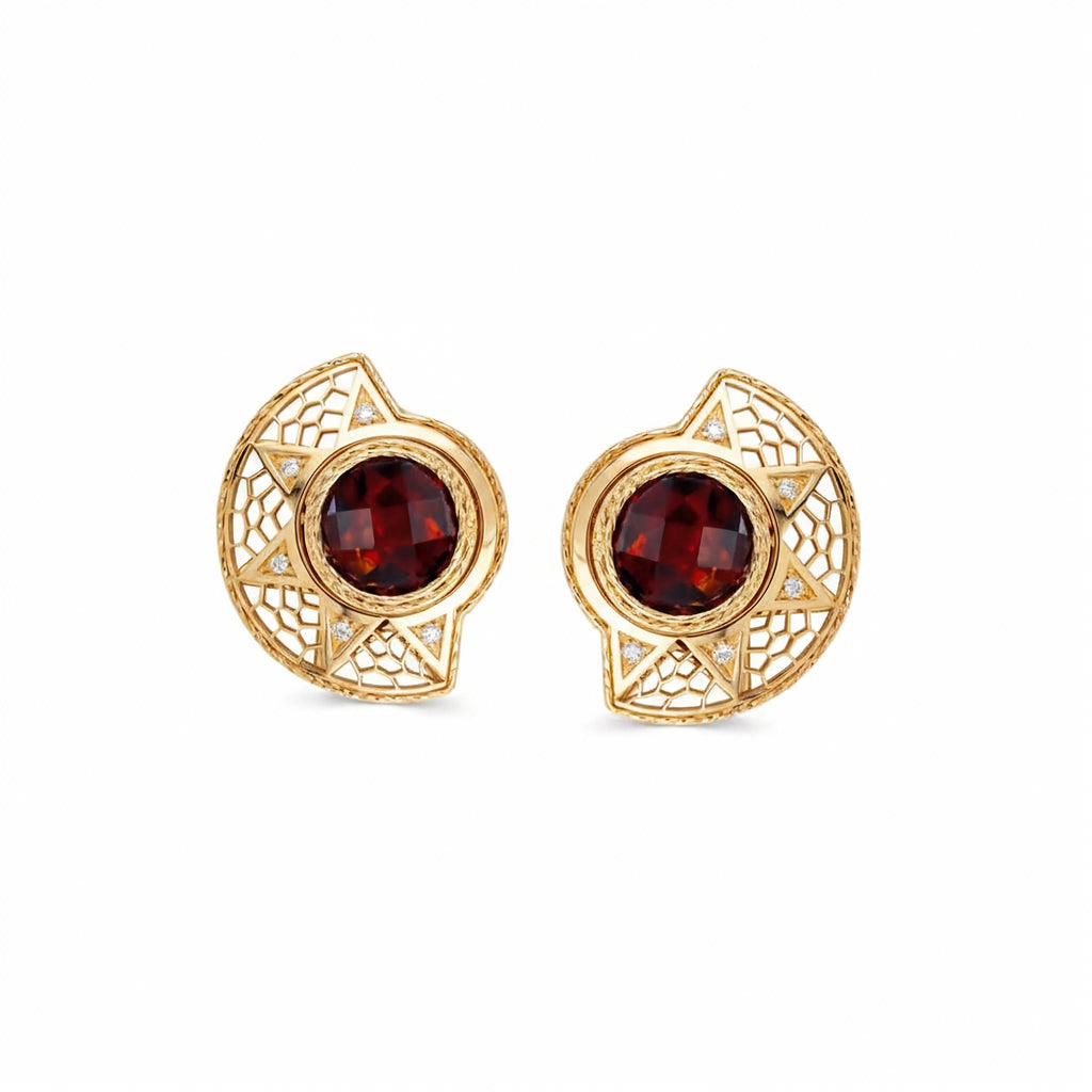 A pair of gold filigree stud earrings featuring round deep red garnet centers and small clear accent stones, shown on a plain white background.